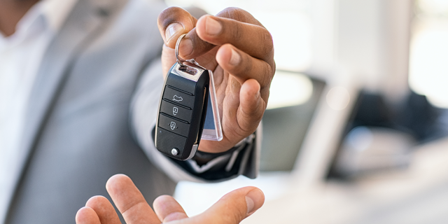 Ejecutivo en traje entrega llaves de un coche a una persona