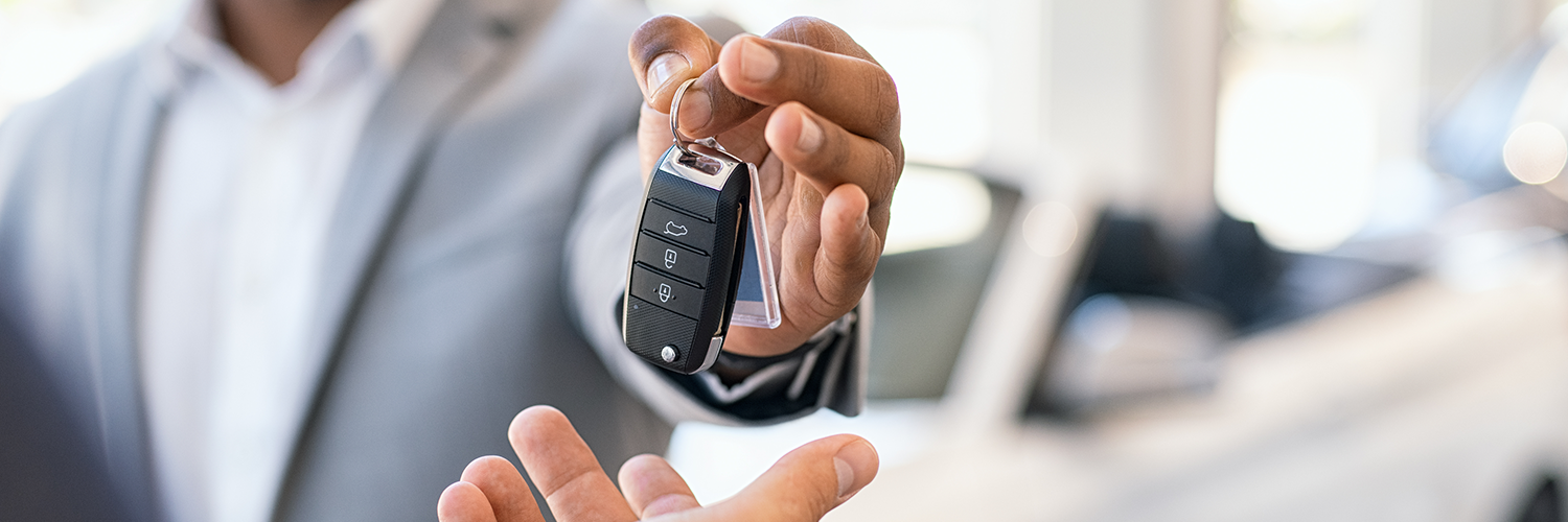 Ejecutivo en traje entrega llaves de un coche a una persona